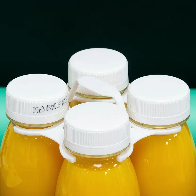 Underside detail showing the grip and ring structural design of a 4-bottle plastic carrier.